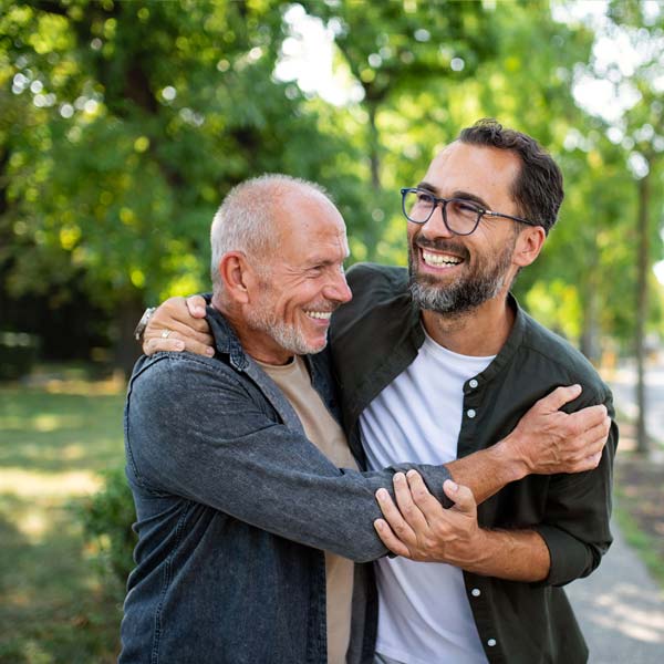 Padre anziano e figlio si abbracciano in un parco