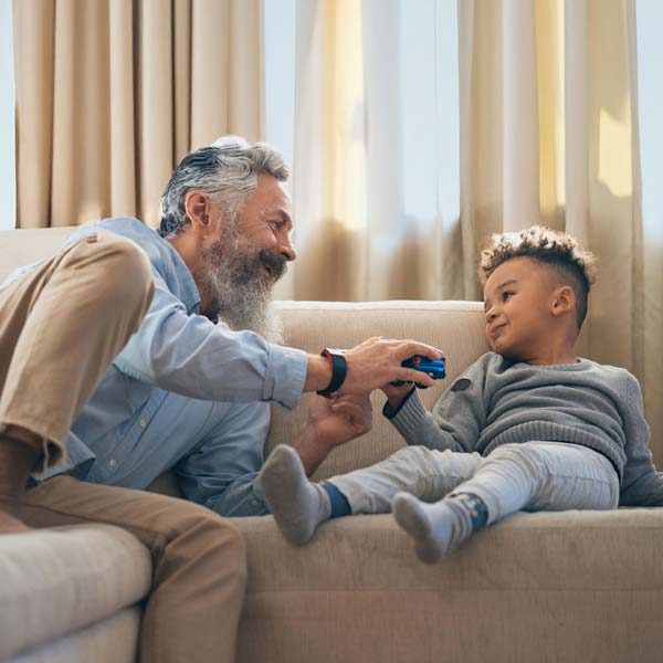 Uomo di mezza età e bambino sorridenti sul divano