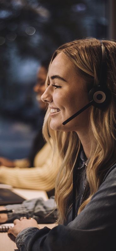 Ragazza bionda di un call center sorride mentre parla al telefono