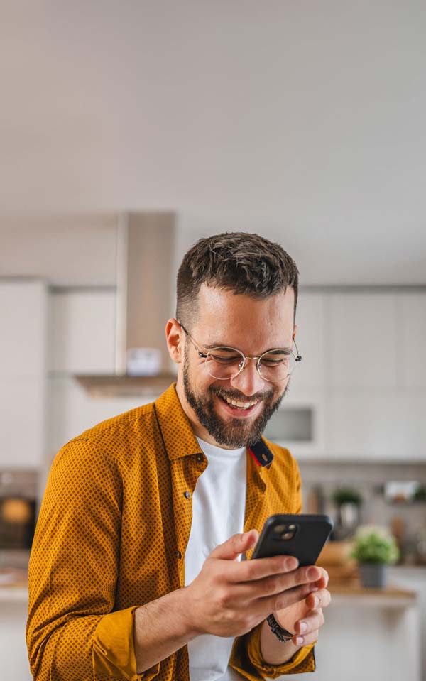 Ragazzo guarda il telefono soddisfatto nella cucina di casa