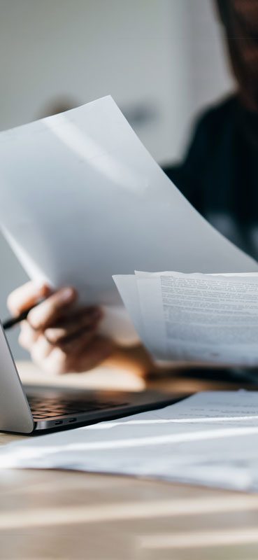 Una donna concentrata di fronte al computer e fogli di lavoro