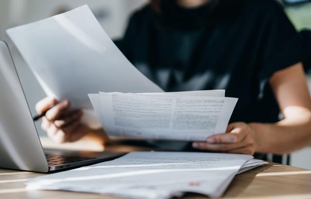 Una donna concentrata di fronte al computer e fogli di lavoro