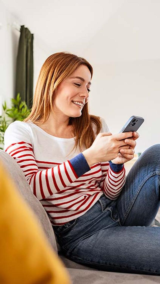 Ragazza legge qualcosa sul suo smartphone seduta sul divano