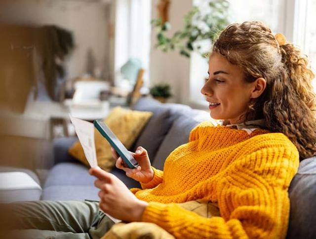 Ragazza con i ricci guarda qualcosa sul proprio smartphone con aria di approvazione