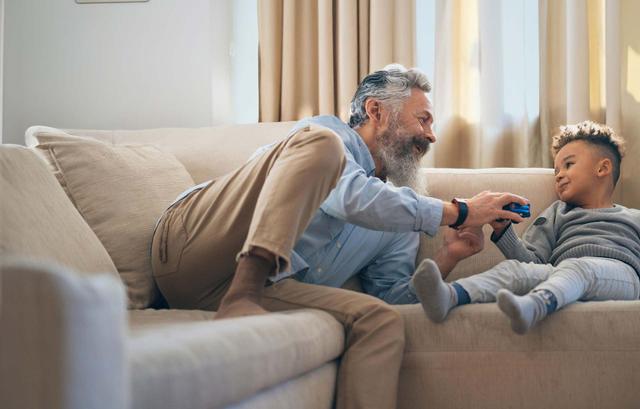 Uomo di mezza età sul divano mentre gioca con un bambino 