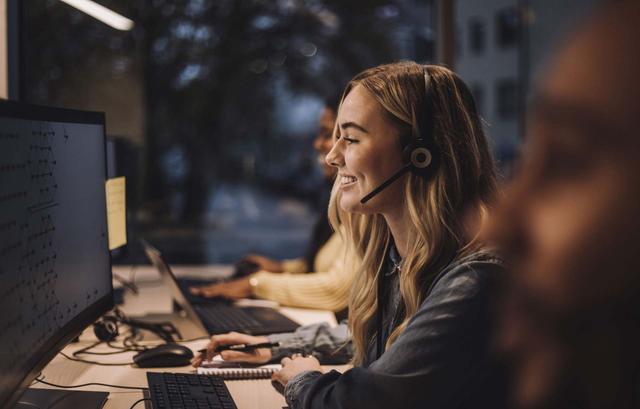Ragazza bionda di un call center sorride mentre parla al telefono