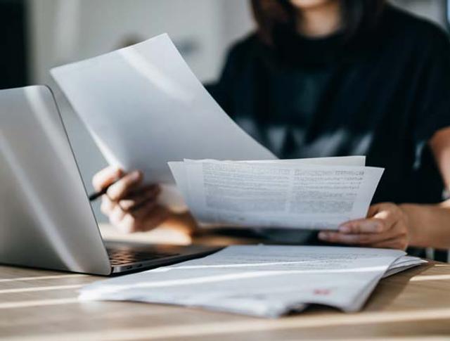 Una donna concentrata di fronte al computer e fogli di lavoro