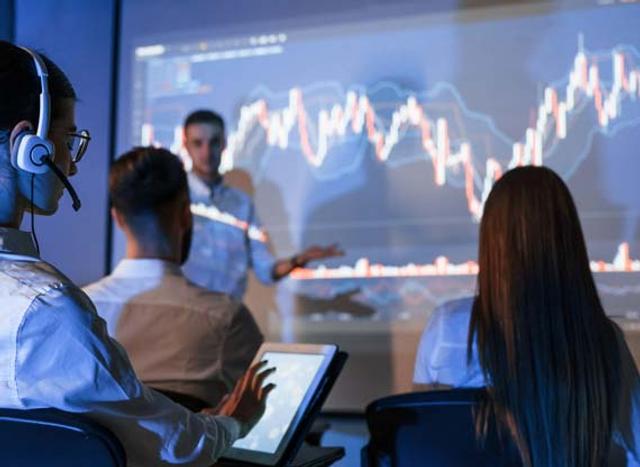 Il team di una azienda discute di fronte ad uno schermo con grafici