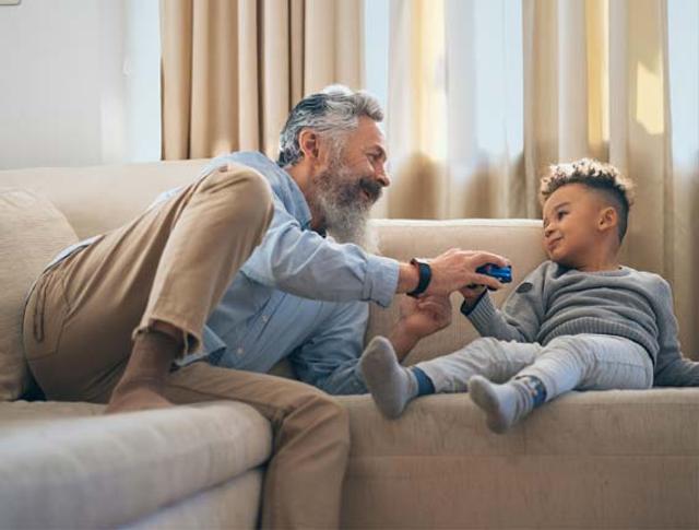 Uomo di mezza età e bambino sorridenti sul divano